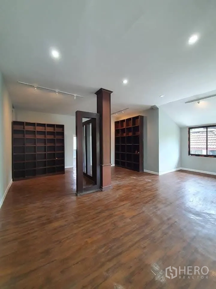 Home Office for rent in Wang Thonglang, Bangkok - Spacious room with wood flooring, recessed lights and built‑in dark shelving.