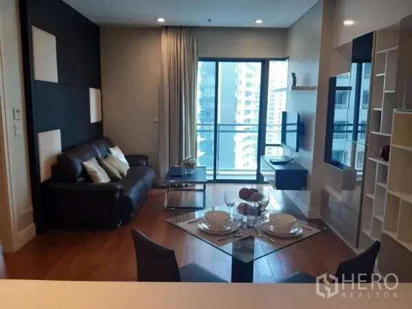 คอนโด ให้เช่าในKhlong Toei, Bangkok - ห้องนั่งเล่นคอนโดในคลองเตย พร้อมโซฟาหนัง ทีวีติดผนัง และประตูกระจกเปิดสู่ระเบียงวิวเมือง