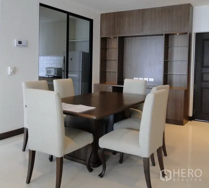 Condominium for rent in Watthana, Bangkok - Dining area beside enclosed kitchen with glass sliding doors and built-in shelving.