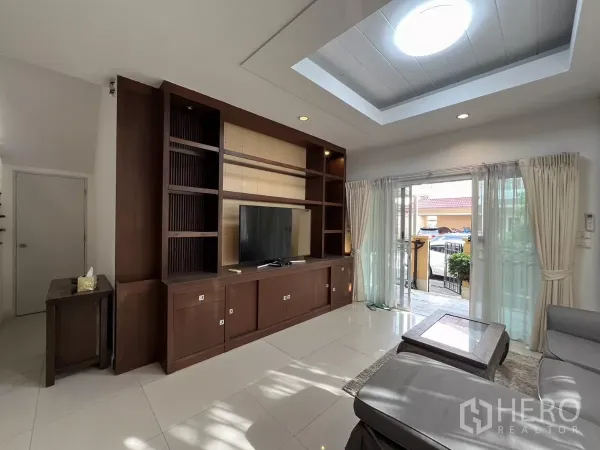 Detached House for rent in Bang Kapi, Bangkok - Bright living room with skylight, built-in TV wall and sliding glass doors to the patio.