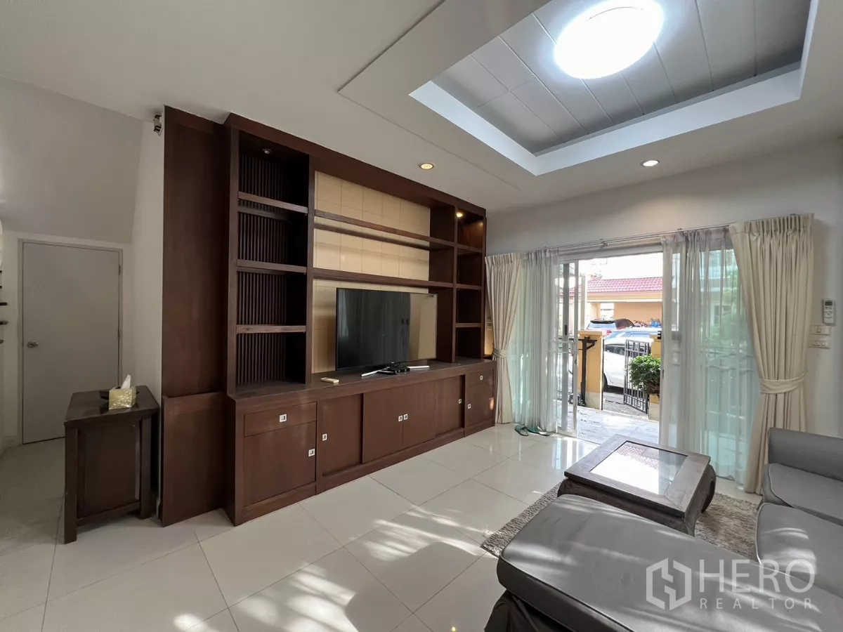Detached House for rent in Bang Kapi, Bangkok - Bright living room with skylight, built-in TV wall and sliding glass doors to the patio.
