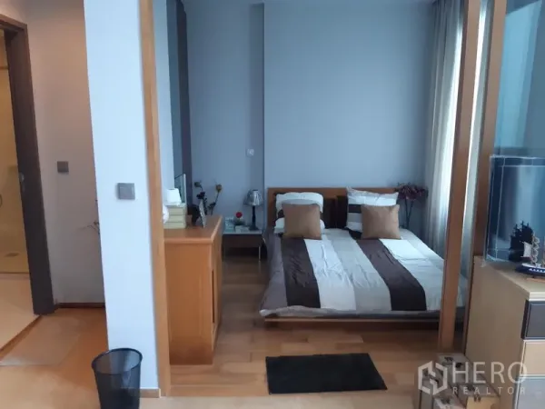 Condominium for rent in Khlong Toei, Bangkok - Cozy secondary bedroom with double bed, side tables, and warm wood flooring.