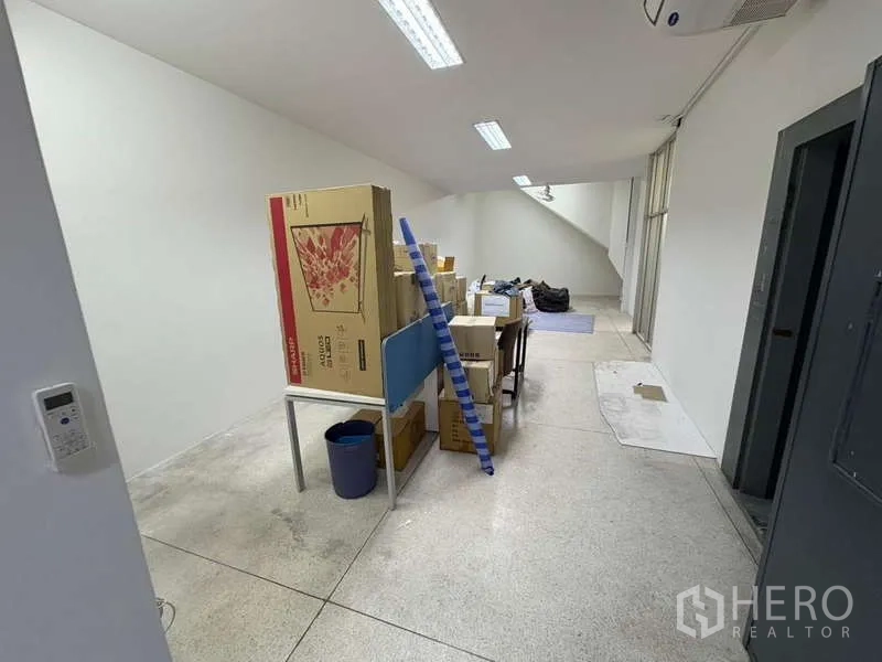 独立商业地产 出租在Khlong Toei, Bangkok - 工作区另一角度，可见纸箱与蓝白条塑料布。