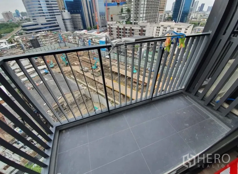 Condominium for rent in Chatuchak, Bangkok - Balcony with metal railing overlooking the city skyline and construction below.