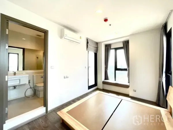 Condominium for rent in Chatuchak, Bangkok - Bedroom with en-suite bathroom and a window seat, featuring multiple large windows.