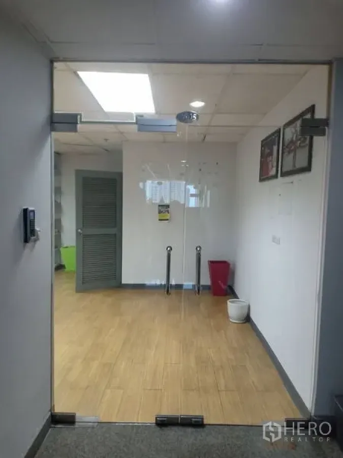 Office Space for rent - View through glass entry door into clean office lobby with wooden floors, white walls and recessed lighting.