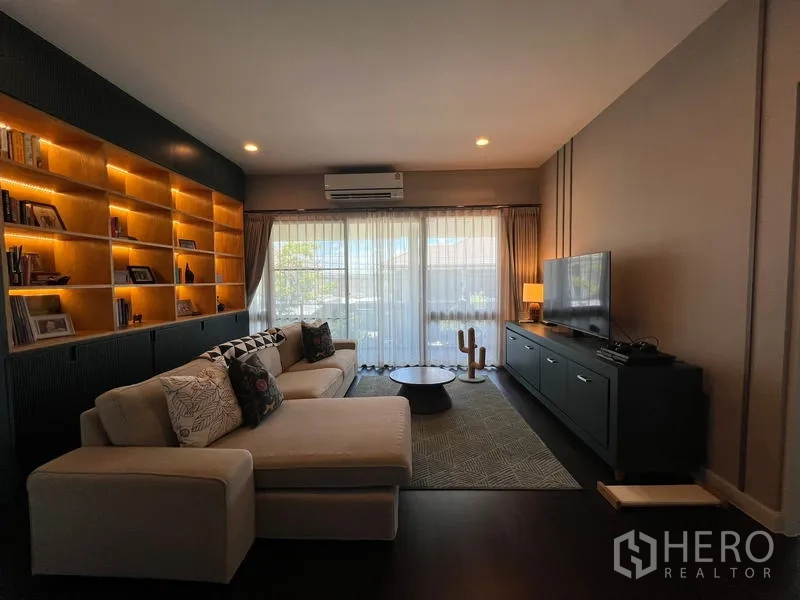Detached House for rent in Bang Kapi, Bangkok - Upstairs family room with sectional sofa, TV console and backlit shelving.