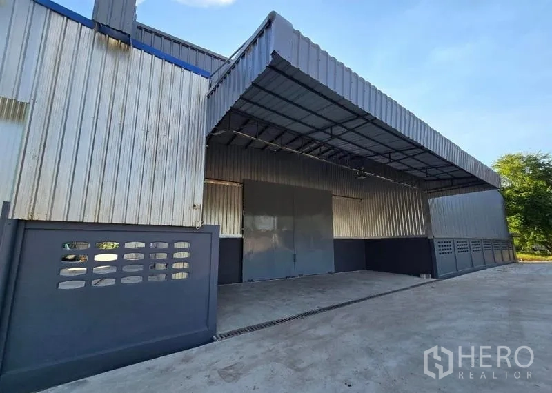 货栈 出租在Sai Noi, Nonthaburi - 仓库入口近景，配大型钢制推拉门与深遮雨雨棚，便于装卸。