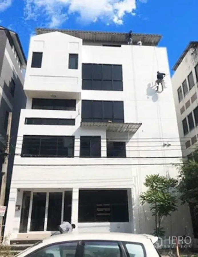 Office Space for rent or sale in Don Mueang, Bangkok - Modern mid-rise white office building exterior with black-framed windows under a blue sky.