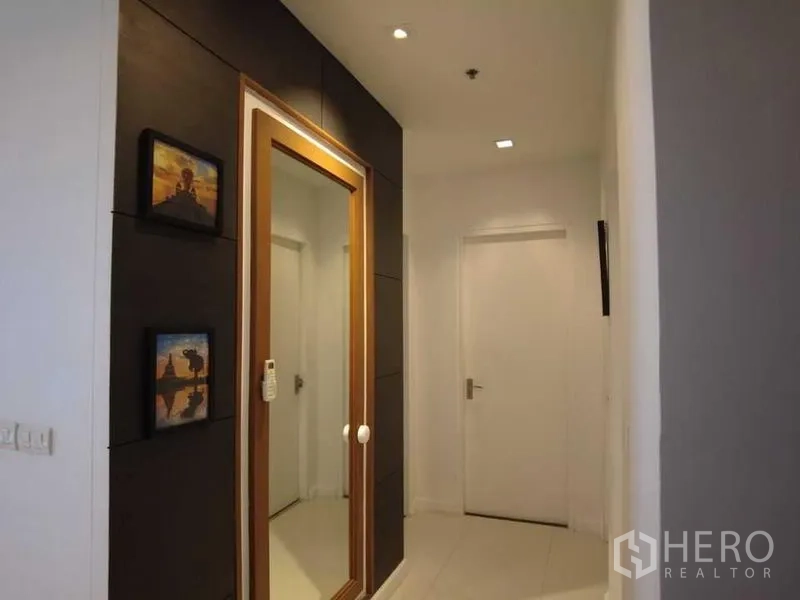 Condominium for rent in Watthana, Bangkok - Corridor with full-height mirror and white doors to bedrooms and baths.