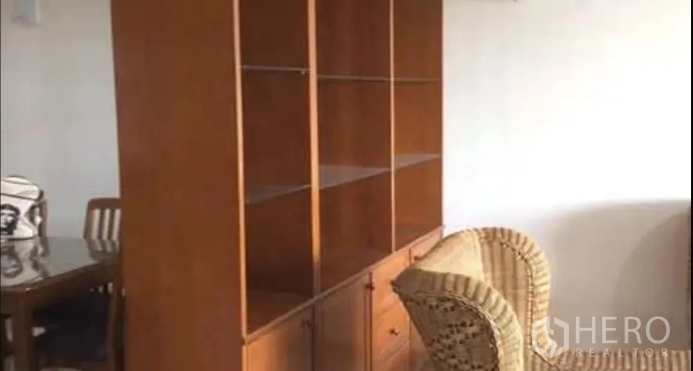 公寓 for sale in Watthana, Bangkok - 客厅配有高大的木质置物柜、藤椅和餐桌椅。