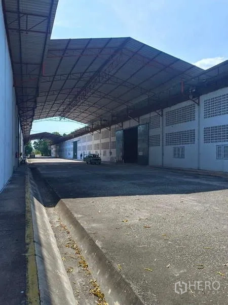 货栈 出租在Mueang Rayong, Rayong - 沿仓库墙的阴凉装卸区，带路缘与排水沟。