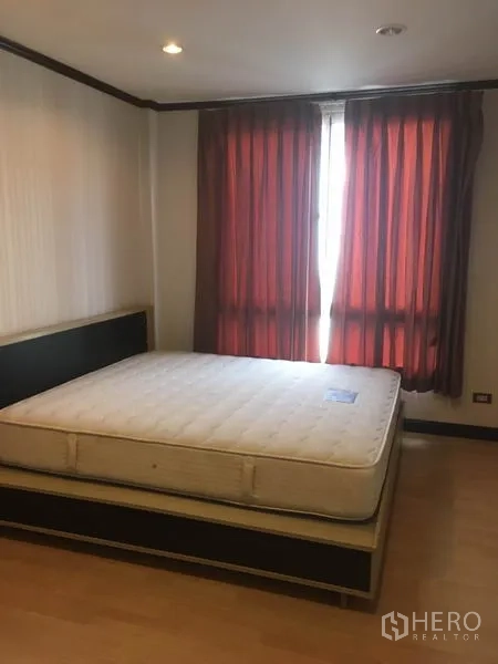 Townhouse for rent in Din Daeng, Bangkok - Second bedroom with large bed, wood floors and red curtains.