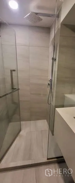 Condominium for rent - Glass-enclosed shower with rain shower head and neutral tiles.