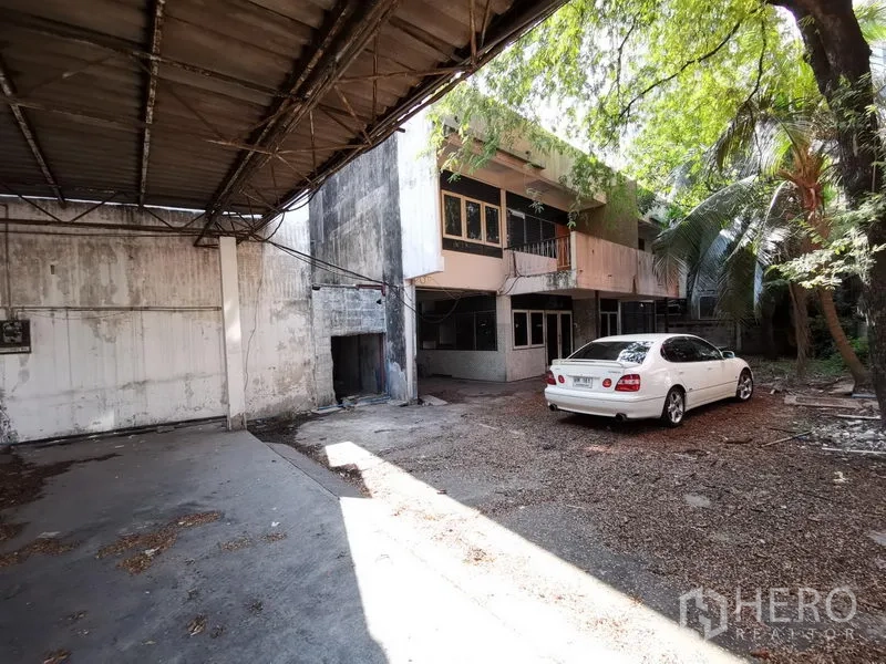 Home Office for rent in Khlong Toei, Bangkok - Front yard with parked car, canopy roof and two-storey building in the background.