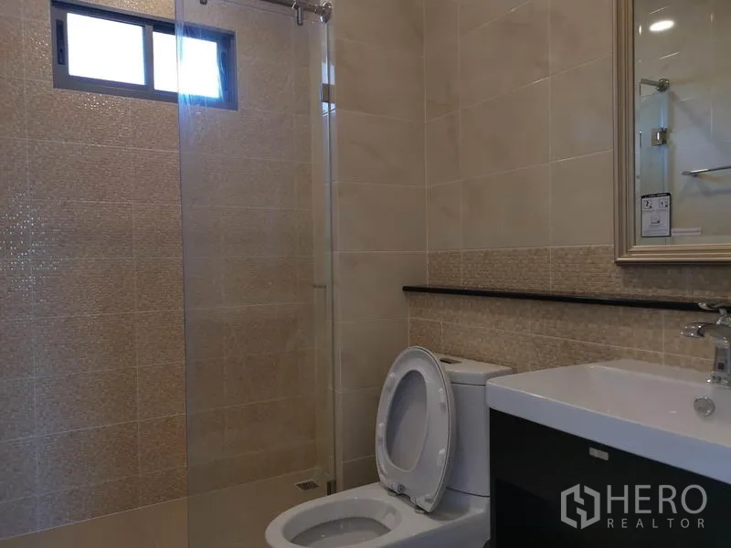 Detached House for sale in Nonthaburi - Tiled bathroom with glass-enclosed shower, toilet and vanity.