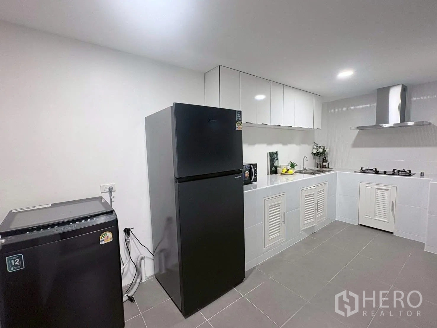 联排别墅 for rent in Huai Khwang, Bangkok - 厨房一角，冰箱和洗衣机并列于橱柜旁。