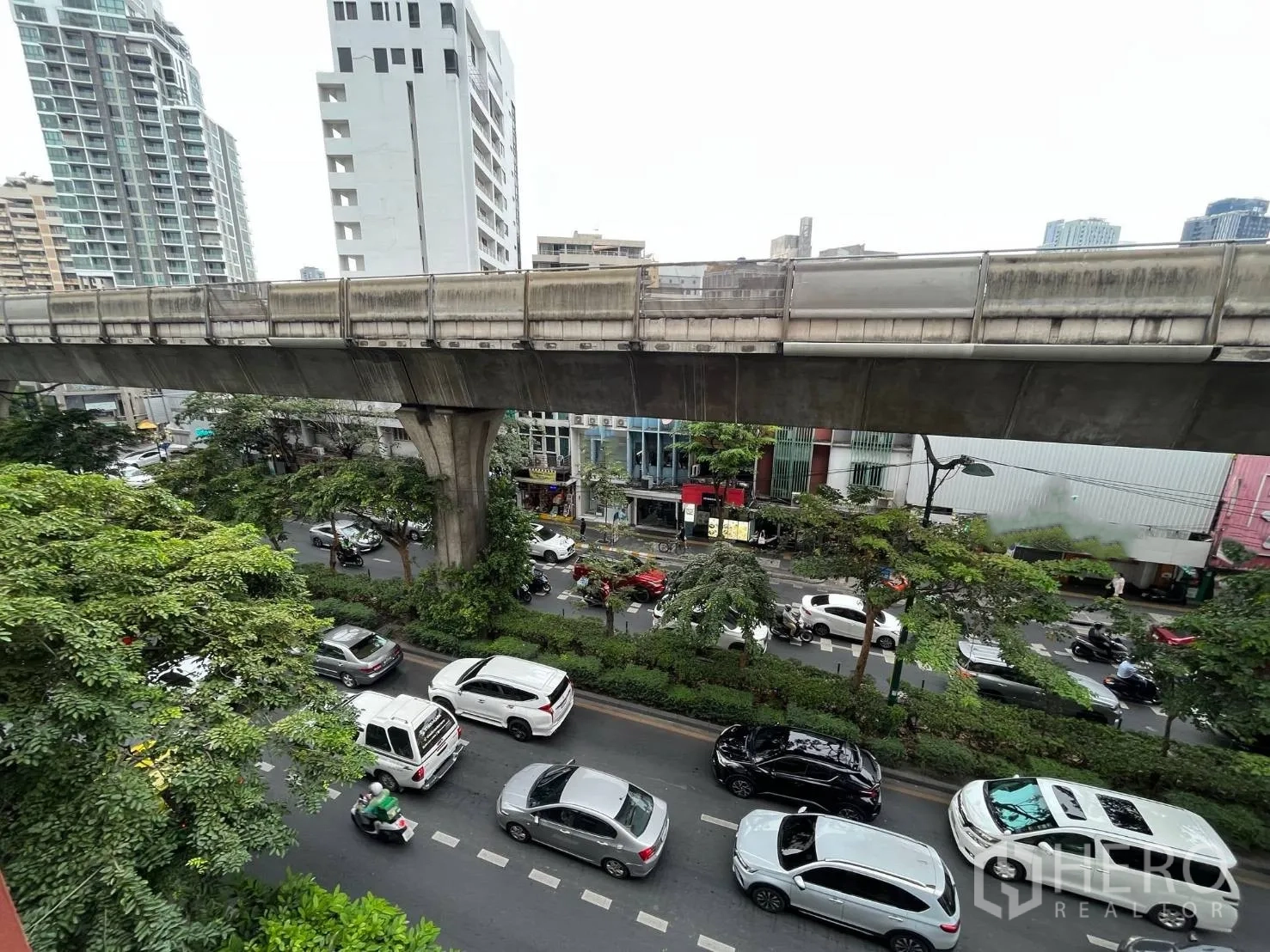 Shophouse for rent in Khlong Toei, Bangkok - BTS Skytrain track running over a main road with heavy traffic and greenery.