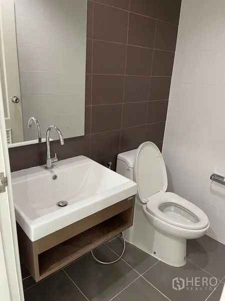 Townhouse for rent in Bang Kapi, Bangkok - Guest bathroom with square sink, mirror, toilet and brown accent wall.