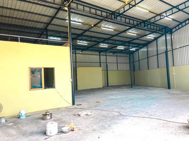 Warehouse for rent in Sai Mai, Bangkok - Clear-span storage area with metal walls, bright strip lighting and smooth concrete flooring.