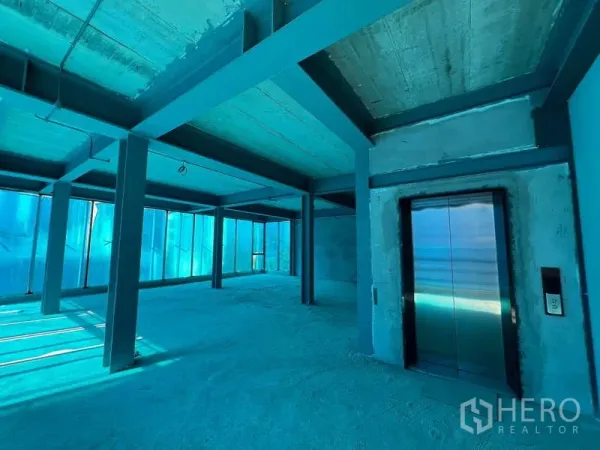 零售空间 出租在Pathum Wan, Bangkok - 开放式毛坯零售楼层，钢结构与混凝土顶，落地窗与不锈钢电梯。