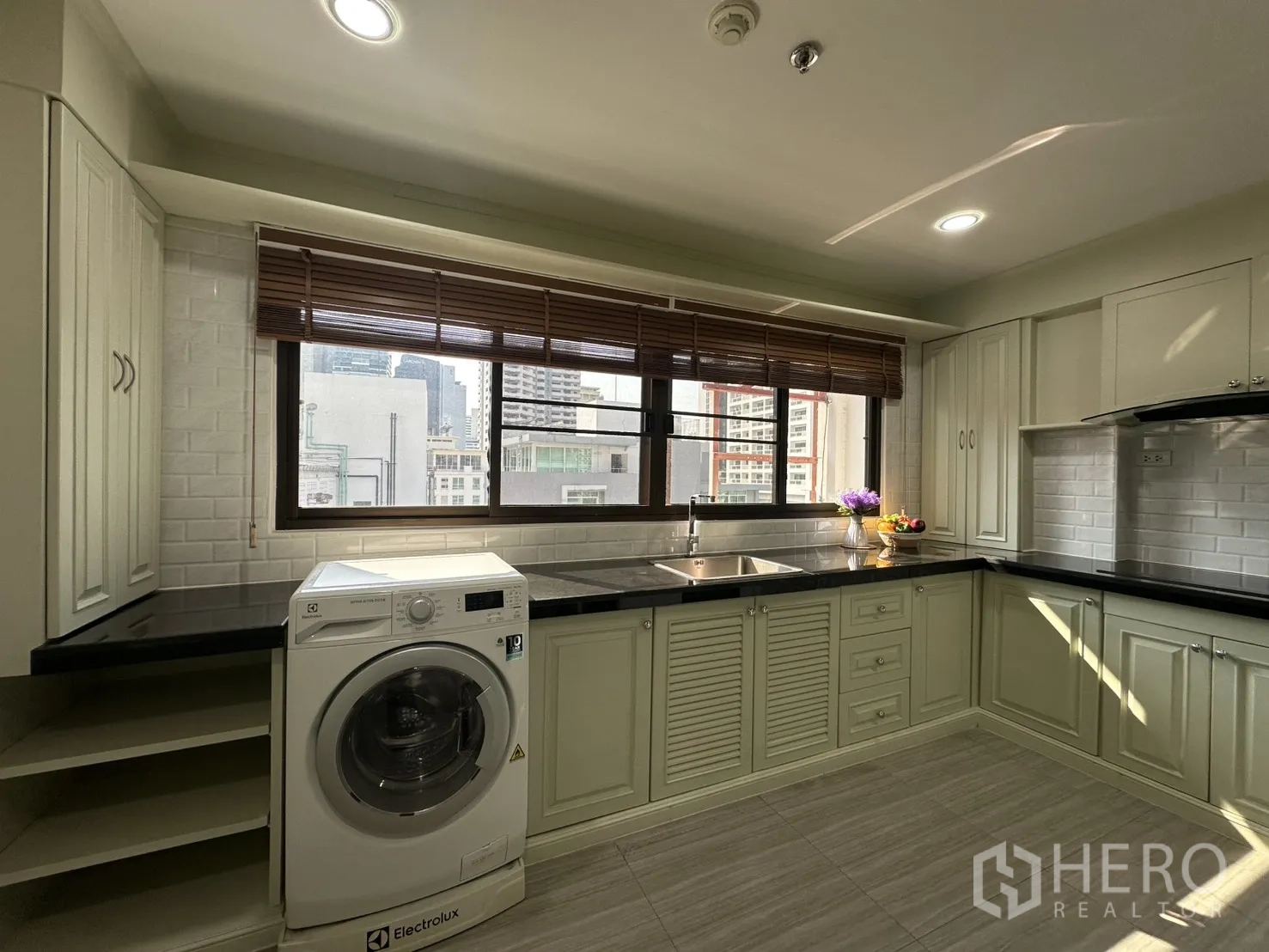 Condominium for rent in Watthana, Bangkok - Kitchen view with large window, sink, and front-load washer.