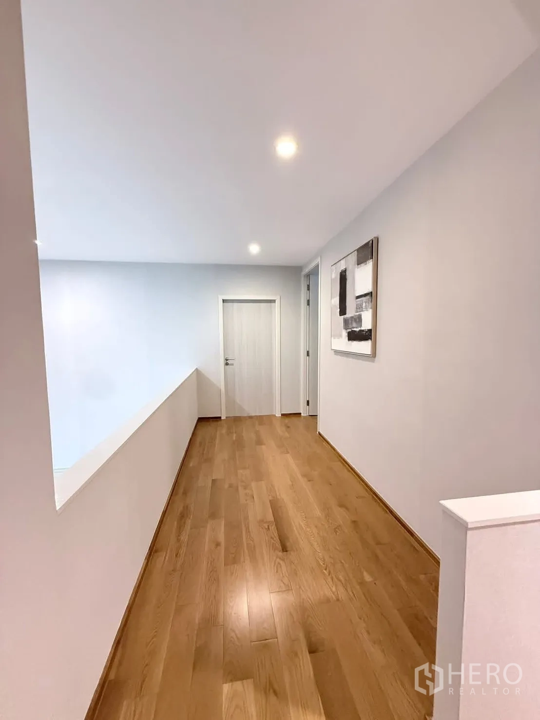 Townhouse for rent in Saphan Sung, Bangkok - Upper hallway with wood floors, white walls and recessed lighting.