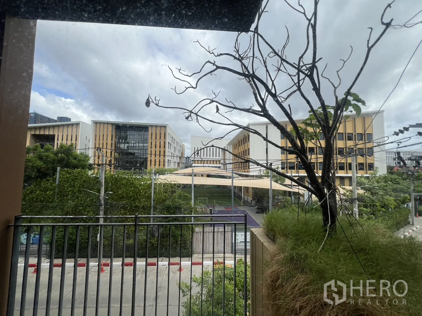 Condominium for rent in Watthana, Bangkok - Balcony view over greenery and modern low-rise buildings beyond.