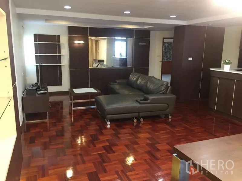 公寓 出租在Khlong Toei, Bangkok - 宽敞客厅，转角皮沙发、内置柜、嵌灯与亮泽拼花木地板