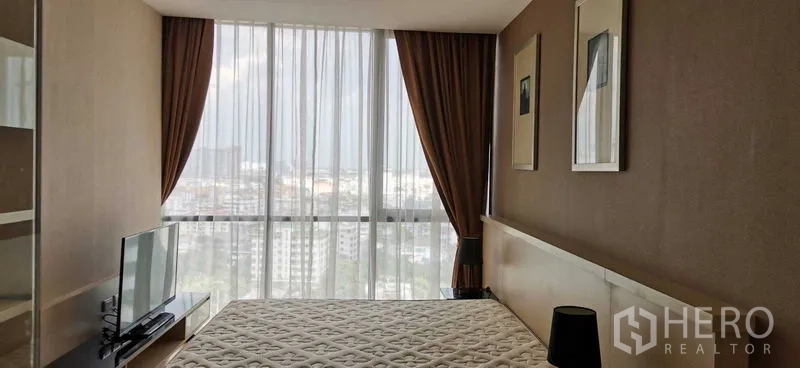 公寓 出租在Watthana, Bangkok - 主卧配大窗与遮光窗帘，可见城市天际线。