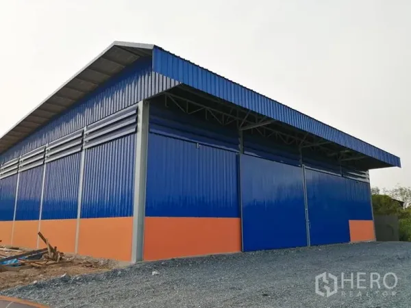 Warehouse for rent in Phra Samut Chedi, Samut Prakan - Side view of blue metal-clad warehouse with high roof and multiple sliding doors.