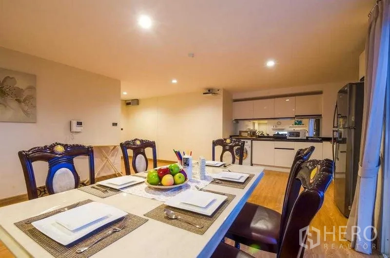 คอนโด ให้เช่าในKhlong Toei, Bangkok - ชุดโต๊ะอาหารแบบทางการ มองไปยังครัวดีไซน์เรียบหรูและตู้เย็นสแตนเลส