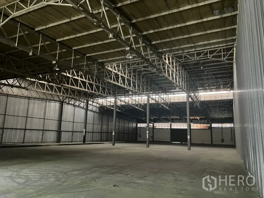 Factory for rent in Bang Pakong, Chachoengsao - Wide warehouse interior with a 7 m steel truss roof, skylights and concrete floor at a Bang Pakong factory.