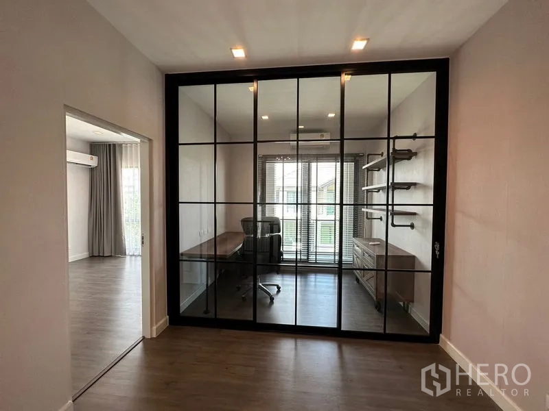 Detached House for rent or sale - Home office behind black-framed glass partition with desk, shelves and window blinds.