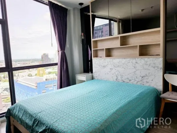 คอนโด ให้เช่าในWatthana, Bangkok - ห้องนอนมุมกระจกวิวเมือง ผ้าปูที่นอนสีเขียว หัวเตียงมีชั้นวาง พร้อมโต๊ะข้างและผ้าม่านทึบ