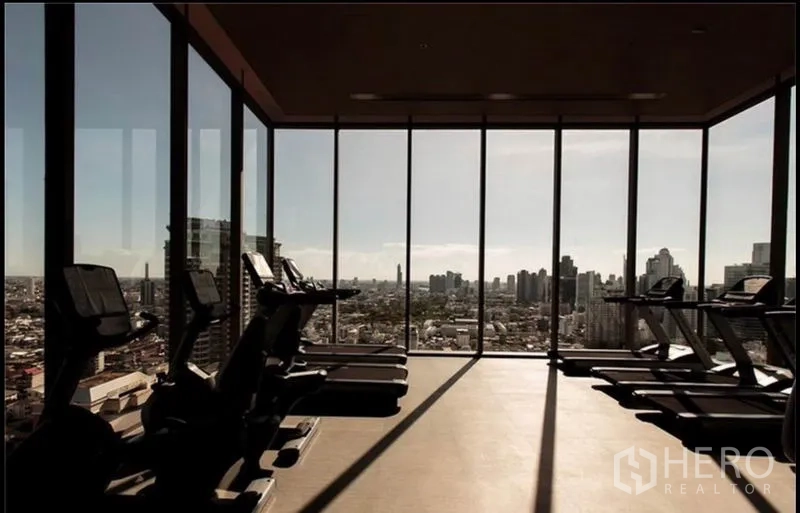 Condominium for rent in Bang Rak, Bangkok - Glass-walled fitness center with treadmills facing a wide city panorama.