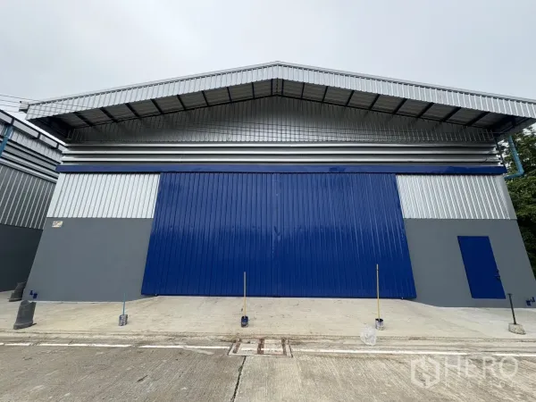 货栈 出租在Bang Phli, Samut Prakan - 金属外墙仓库外观，蓝色大型推拉门与宽阔混凝土车道。