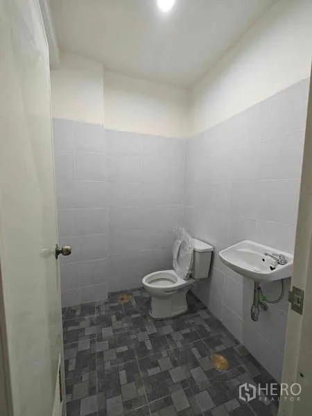 Warehouse for rent in Sam Phran, Nakhon Pathom - Clean tiled restroom inside the warehouse with ceramic toilet and wall-mounted sink.