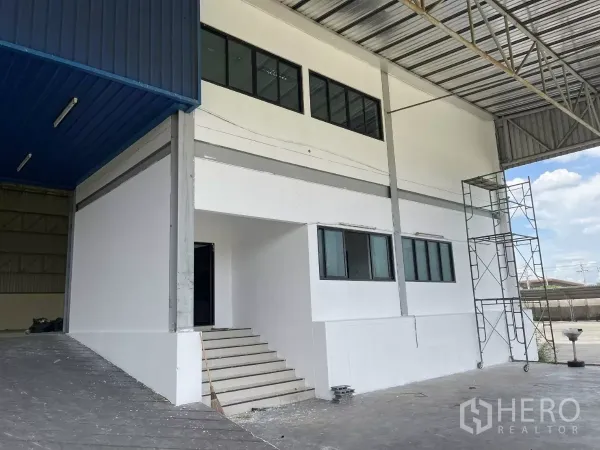 Warehouse for rent in Lat Krabang, Bangkok - Two-storey office block at the warehouse entry with stairs under a metal roof.