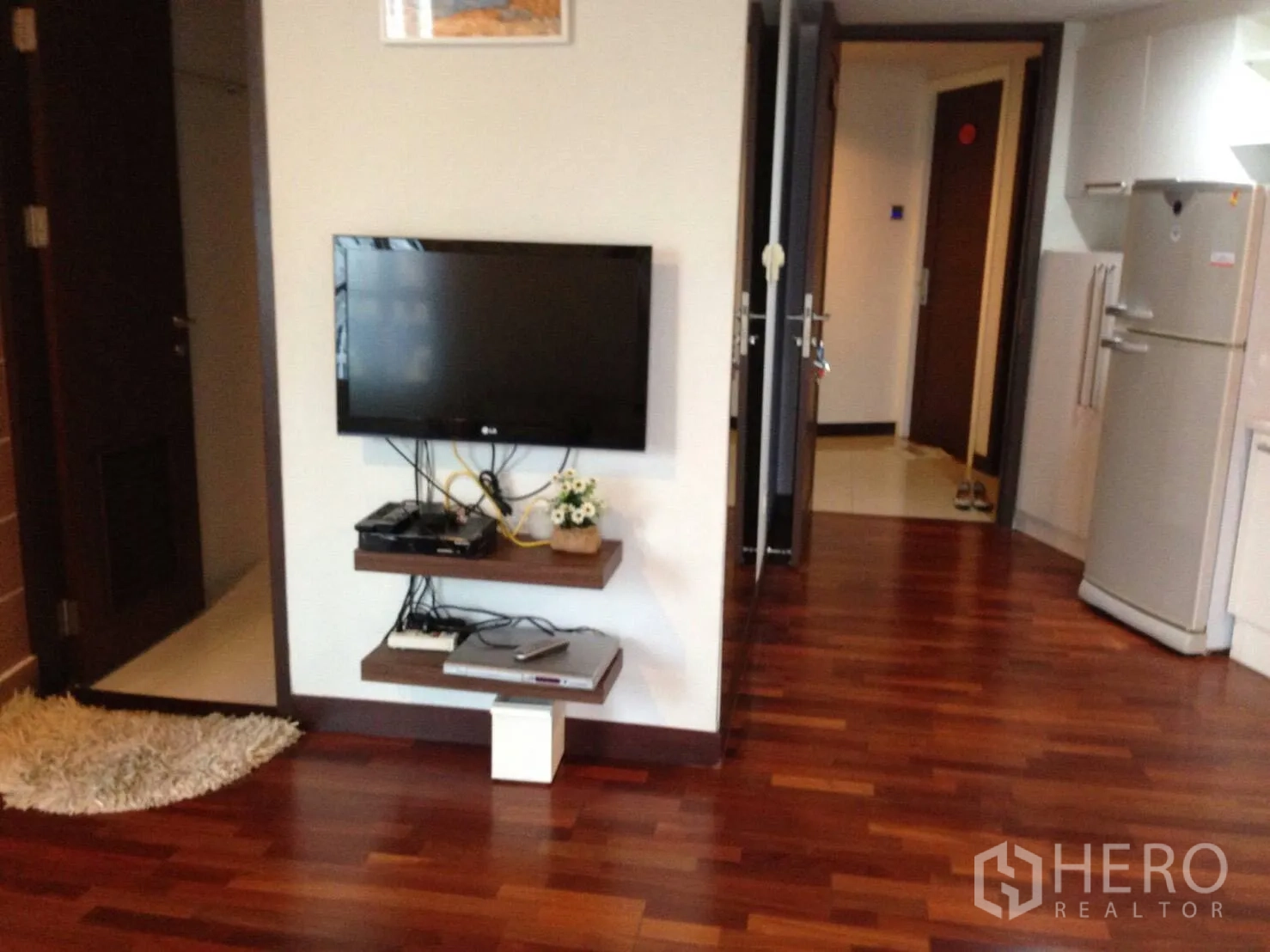 Condominium for rent in Pathum Wan, Bangkok - Wall-mounted TV, hallway and polished wooden floors inside the condominium.