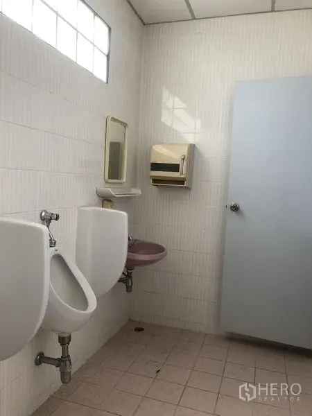 工厂 出租或出售在Bang Lamung, Chon Buri - 整洁的瓷砖卫生间，配小便池、洗手盆、镜子和磨砂玻璃窗。