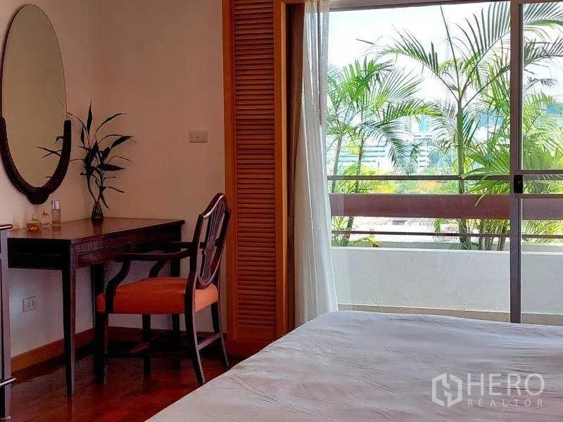 อพาร์ทเมนท์ ให้เช่า - มุมโต๊ะเครื่องแป้งในห้องนอน พร้อมประตูกระจกสไลด์ออกระเบียงมีต้นไม้