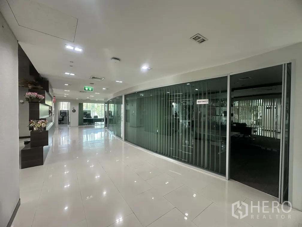 Factory for rent in Lam Luk Ka, Pathum Thani - Bright corporate corridor with glass-walled meeting rooms and polished floors.