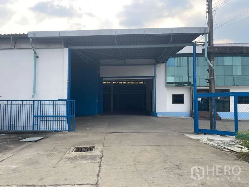 Warehouse for rent in Nong Khaem, Bangkok - Renovated warehouse entrance with a wide driveway, covered loading bay and blue gate in Nong Khaem.