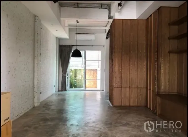 联排别墅 出售在Wang Thonglang, Bangkok - 开放式起居区，水泥抛光地面、吊灯与推拉玻璃门。