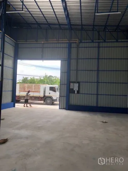 Warehouse for rent in Wang Thonglang, Bangkok - Interior view toward a wide roll-up door showing truck-friendly access and polished concrete floor.