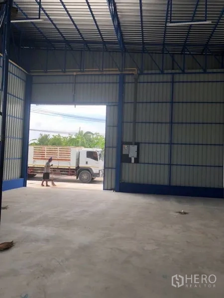 Warehouse for rent in Wang Thonglang, Bangkok - Interior view toward a wide roll-up door showing truck-friendly access and polished concrete floor.