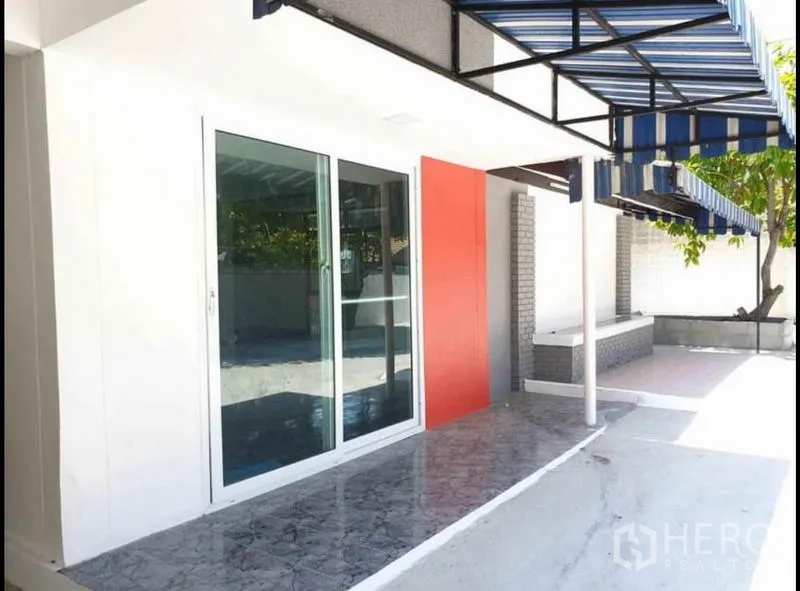 บ้าน ให้เช่าในLat Phrao, Bangkok - ชานบ้านมีกันสาดลายทางสีน้ำเงิน ผนังไฮไลต์สีแดง และประตูกระจกเต็มบาน