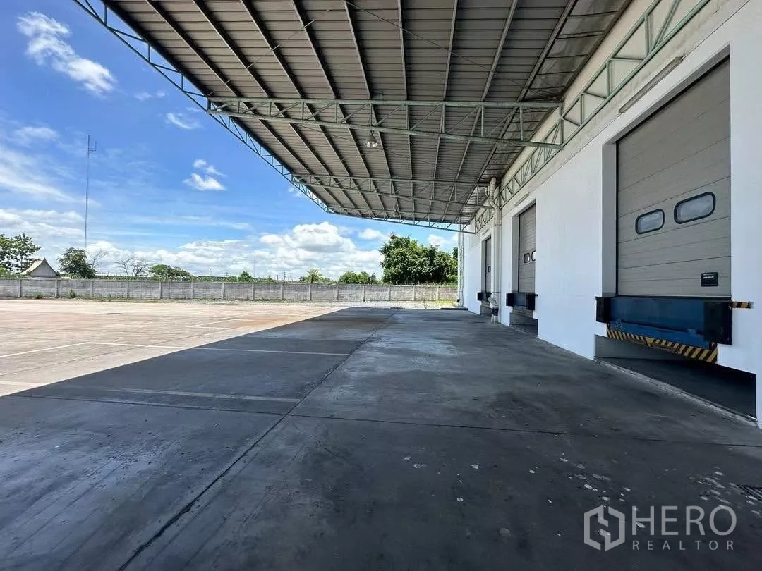 工厂 出租在Si Racha, Chon Buri - 金属雨棚下的宽阔作业坪，适合拖车掉头与装卸。