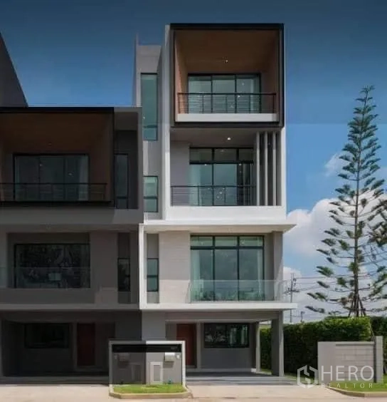 Townhouse for rent in Saphan Sung, Bangkok - Modern multi-level townhouse exterior with large balconies and floor-to-ceiling windows.